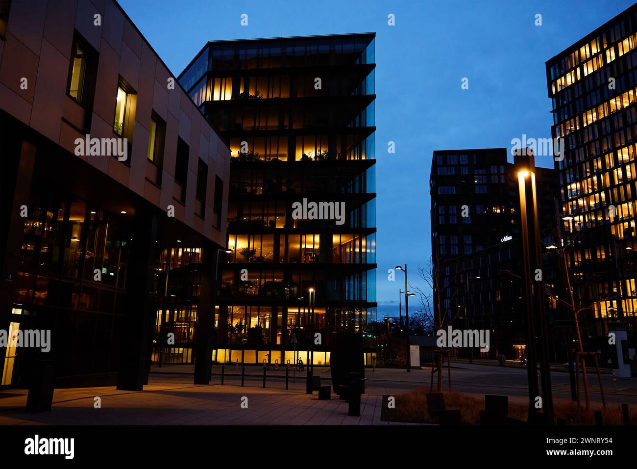 Das Bürogebäude beleuchtet den Abend mit Fenstern, die in der Abenddämmerung leuchten und das städtische Arbeitsleben nach Geschäftsschluss veranschaulichen Stockfoto