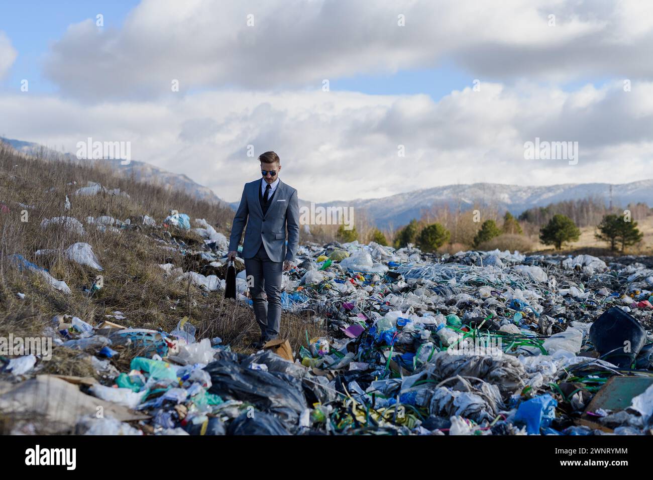 Geschäftsmann, der auf Mülldeponien rüberläuft, großer Müllhaufen. Konsum versus Verschmutzungskonzept. Soziale Verantwortung von Unternehmen im Unternehmen. Stockfoto