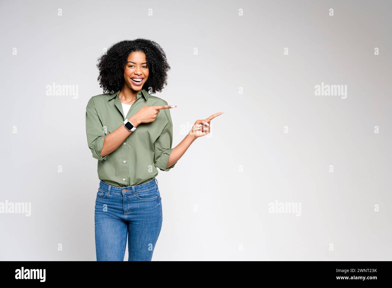 Mit einer einladenden Präsentation zeigt diese afroamerikanische Frau in einem elegant-lässigen Outfit auf ein unsichtbares Produkt, das sich perfekt für Werbung und Werbung eignet. Stockfoto