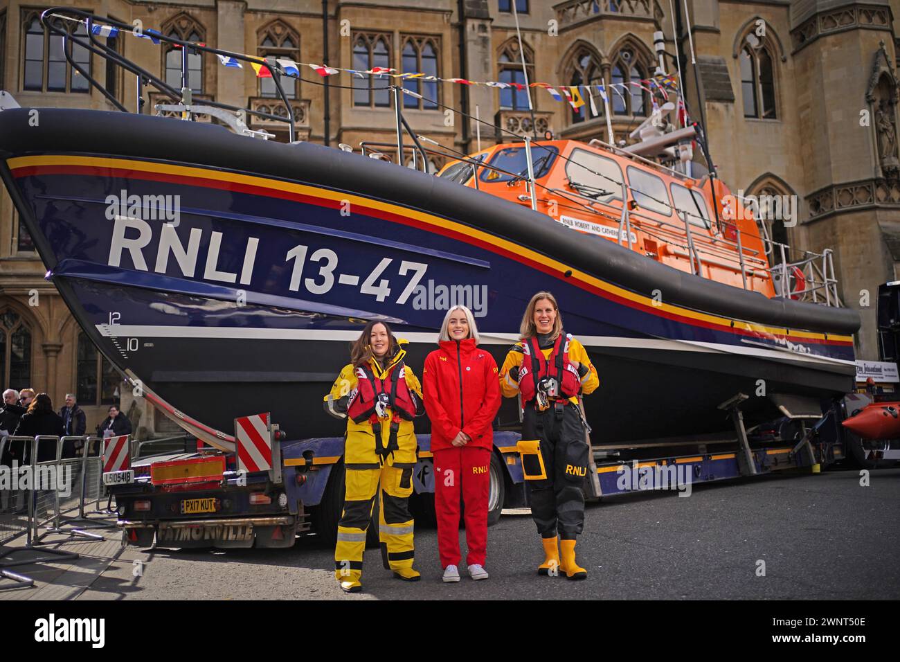 (Von links nach rechts) Besatzungsmitglieder der Royal National Lifeboat Institution (RNLI) Aine Flynn aus Ballycotton Ireland, Nelly Gallichan Senior Beach Lifeguard auf den Jersey Channel Islands und Jen Payne aus Penarth South Wales mit einem RNLI-Rettungsboot vor der Westminster Abbey in London vor einem Dankesgottesdienst zum 200. Jahrestag der RNLI. Bilddatum: Montag, 4. März 2024. Stockfoto