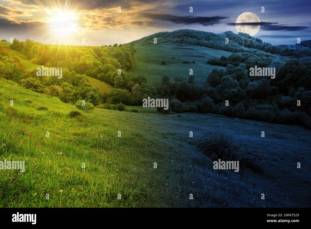 Landschaft mit Wiese in der Nähe des bewaldeten Hügels der bergigen ländlichen Gegend mit Sonne und Mond bei Frühlingspätnachtnachtgleiche. Tag- und Nachtzeitwechsel. Mysteri Stockfoto