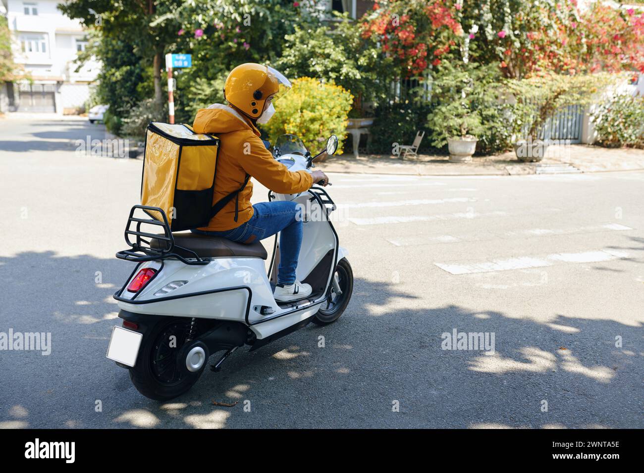 Liefermann in gelber Uniform fahrend Motorrad Stockfoto