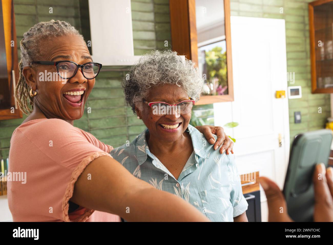 Ältere afroamerikanische Frau und ältere birassische Frau teilen einen freudigen Moment, um ein Selfie zu machen Stockfoto