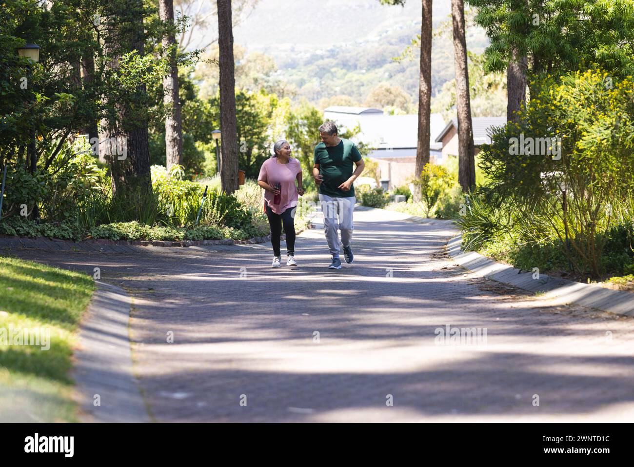 Seniorenpaare genießen einen gemütlichen Spaziergang in einem üppigen, grünen Park mit Kopierraum Stockfoto