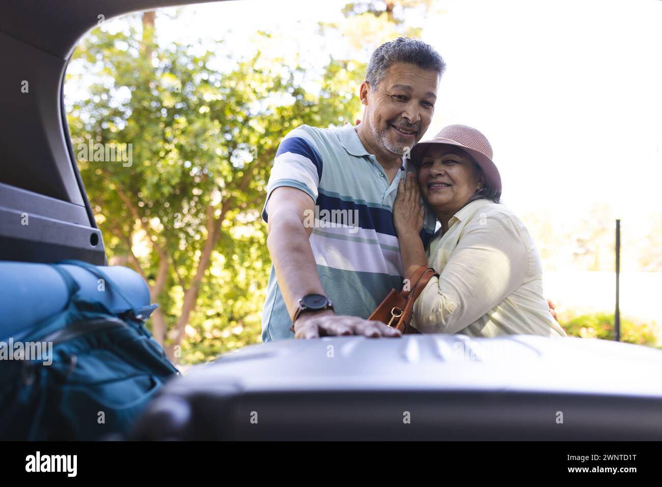 Hochrangiges birassisches Paar, das sich neben einem offenen Kofferraum umschließt, bereit für einen Roadtrip Stockfoto