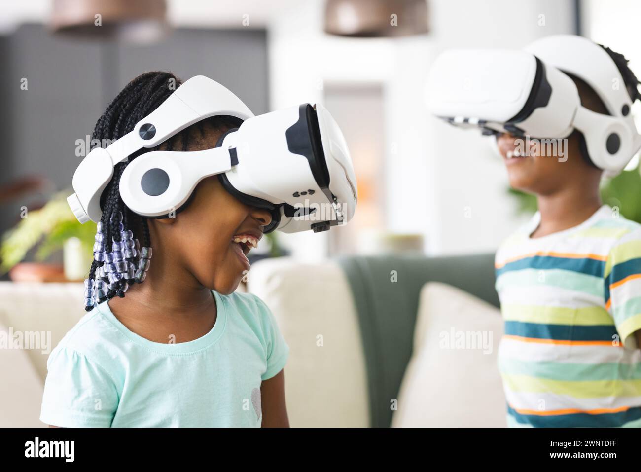 Afroamerikanische Schwester und Bruder tauchen mit VR-Headsets in die virtuelle Realität ein Stockfoto