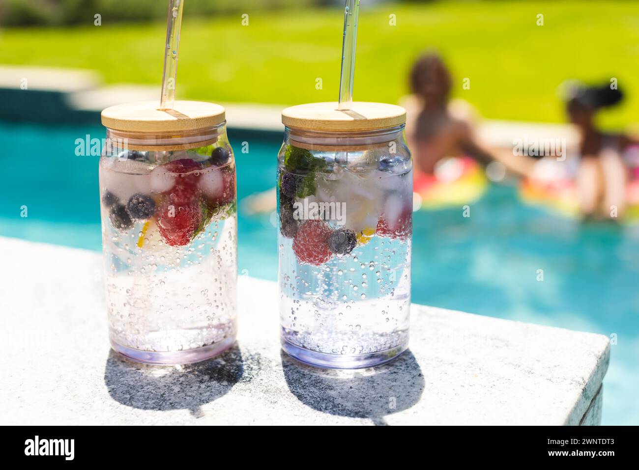 Zwei erfrischende Wassergläser mit Fruchtwasser und Strohhalmen stehen am Pool Stockfoto