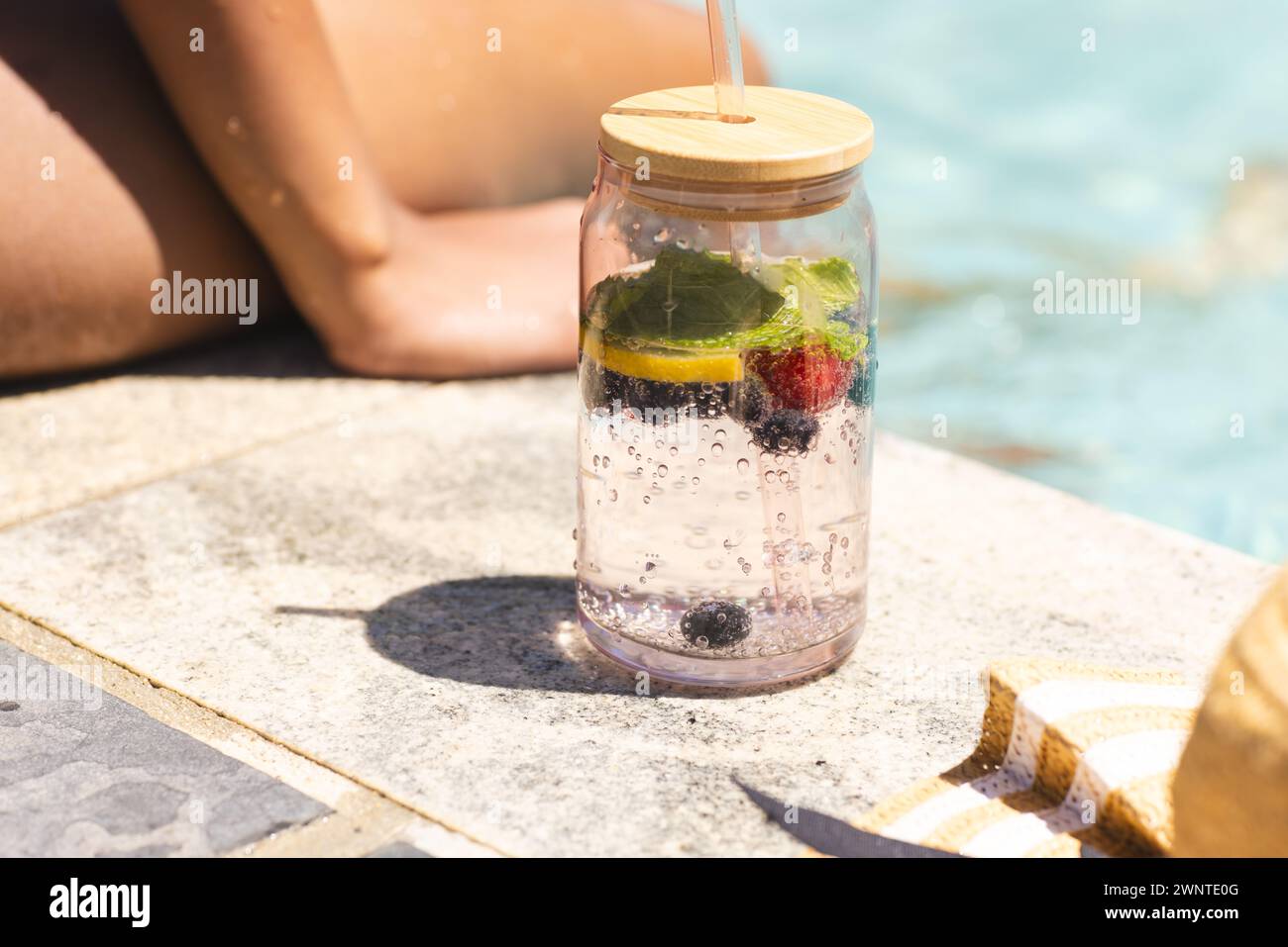 Eine klare Wasserflasche mit Zitronen und Beeren befindet sich am Pool Stockfoto