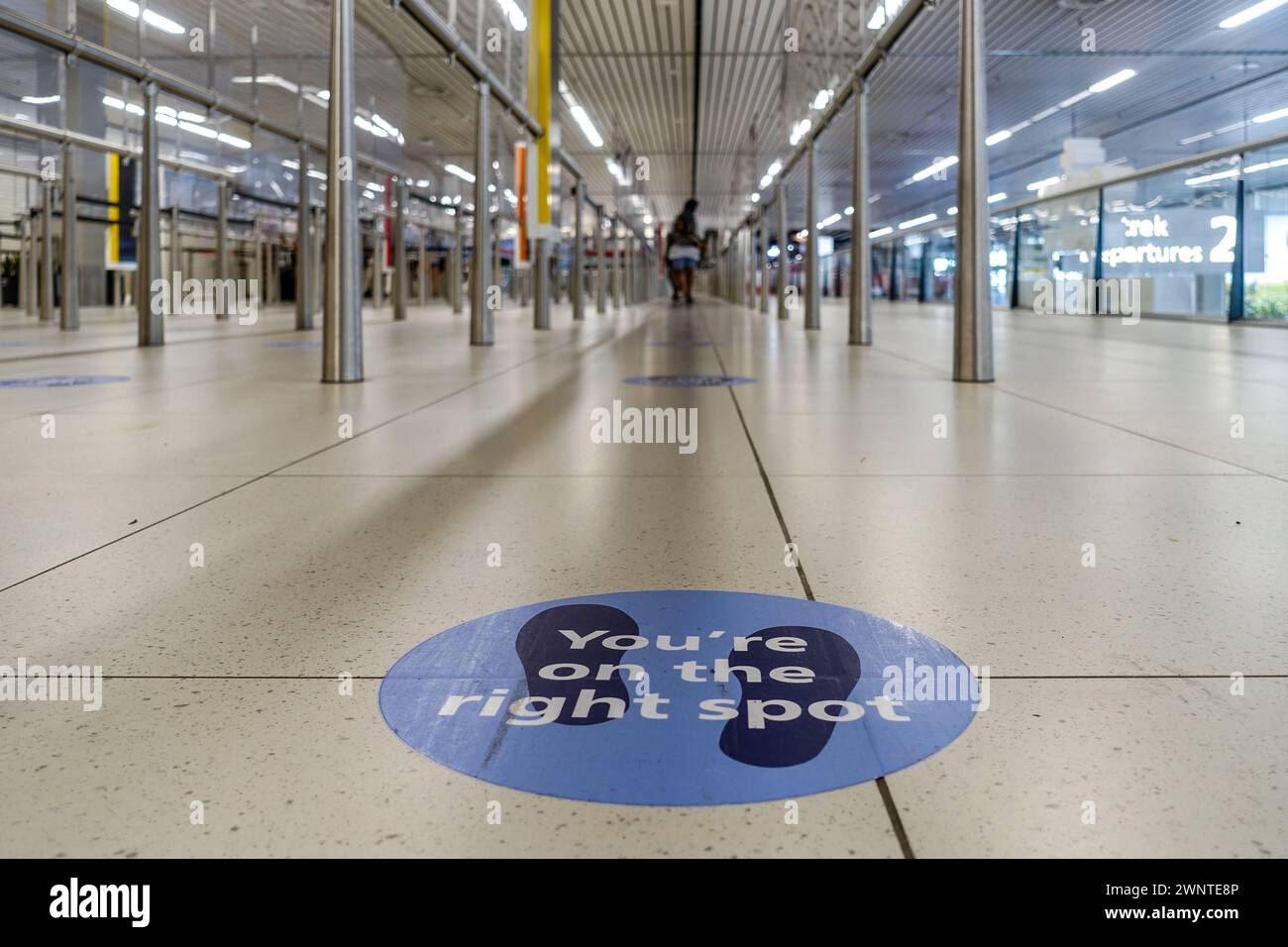 Flacher Blick auf eine leere Flut des Flughafens Schiphol, mit einem Schild „You're on the right Spot“ während covid-Lockdown-Einschränkungen für soziale Distanz Stockfoto