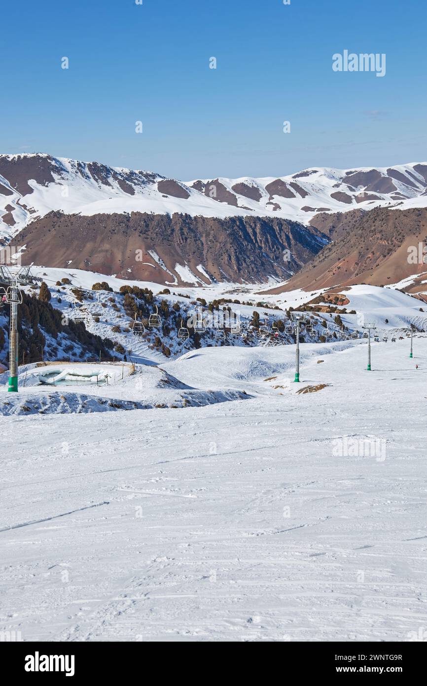 Seilbahnstange, Bau. Winterurlaub Aktivität, Lifestyle Sport und Erholung. Skifahrer und Snowboarder fahren mit dem Skilift hinauf, der zum Gipfel führt Stockfoto