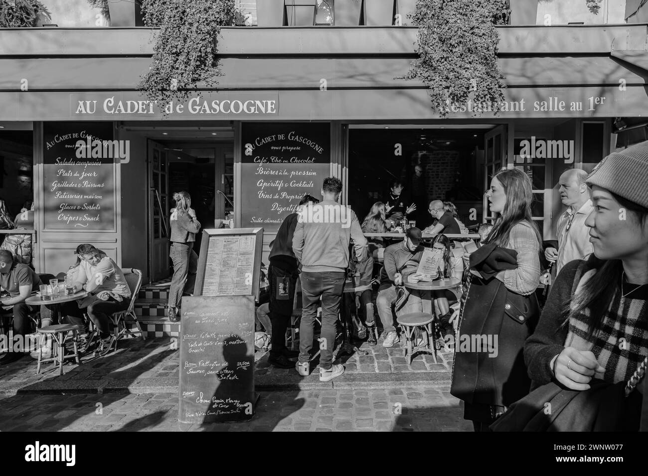 Paris, Frankreich - 17. Februar 2024 : Blick auf die Menschen, die draußen sitzen und in einem Restaurant-Bistro in Montmartre Paris Frankreich Abendessen und Getränke genießen Stockfoto