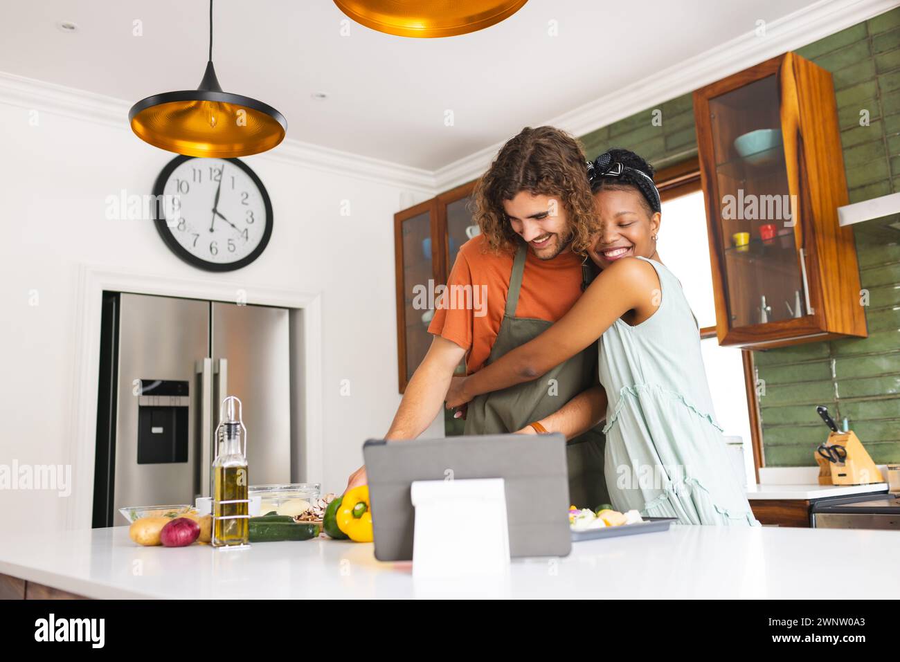 Ein vielseitiges Paar, ein junger Kaukasier und eine Afroamerikanerin teilen sich einen Moment in einer Küche Stockfoto