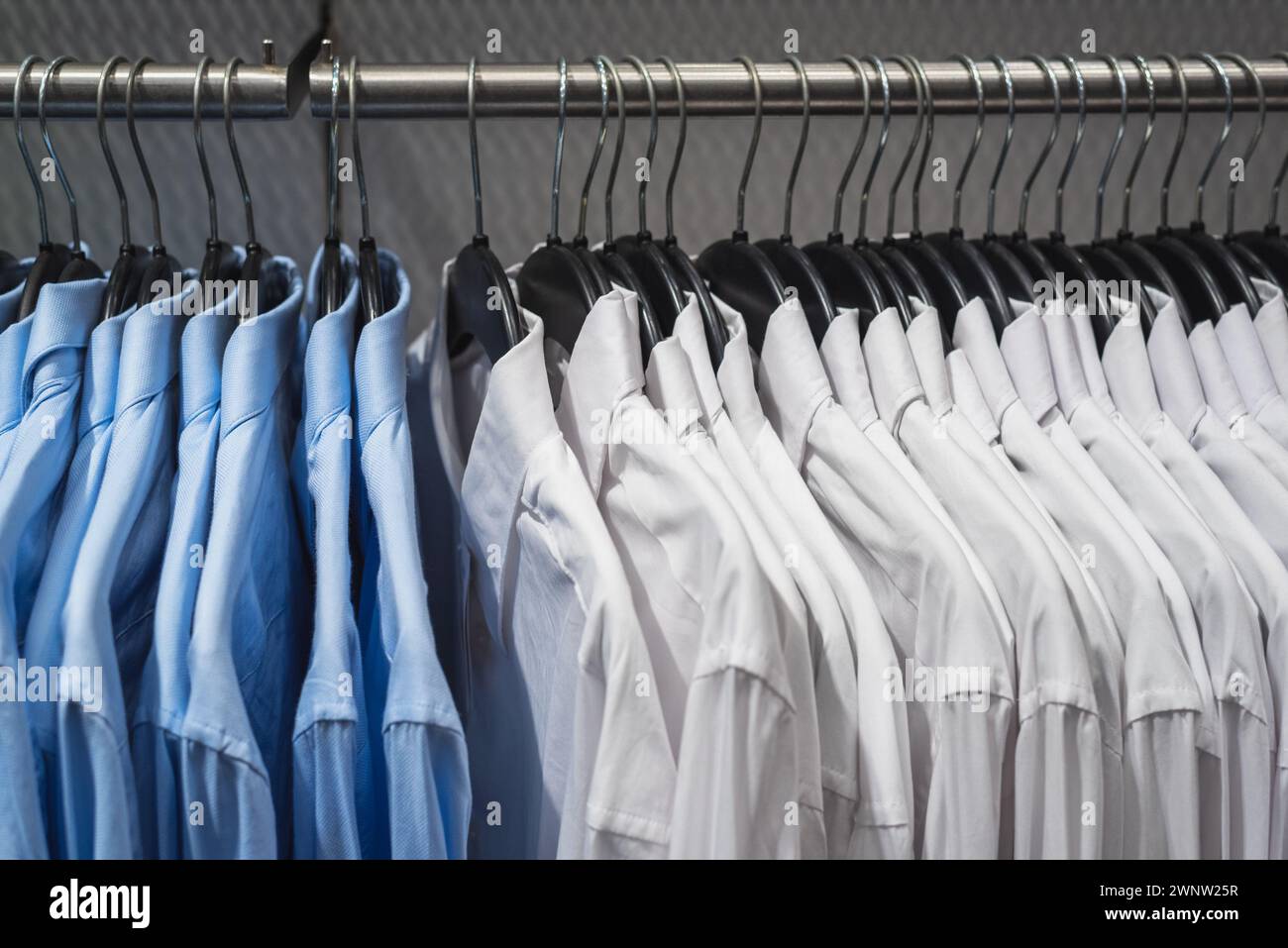 Blau-weiße Hemden an Kleiderbügeln hängen am Regal Stockfoto
