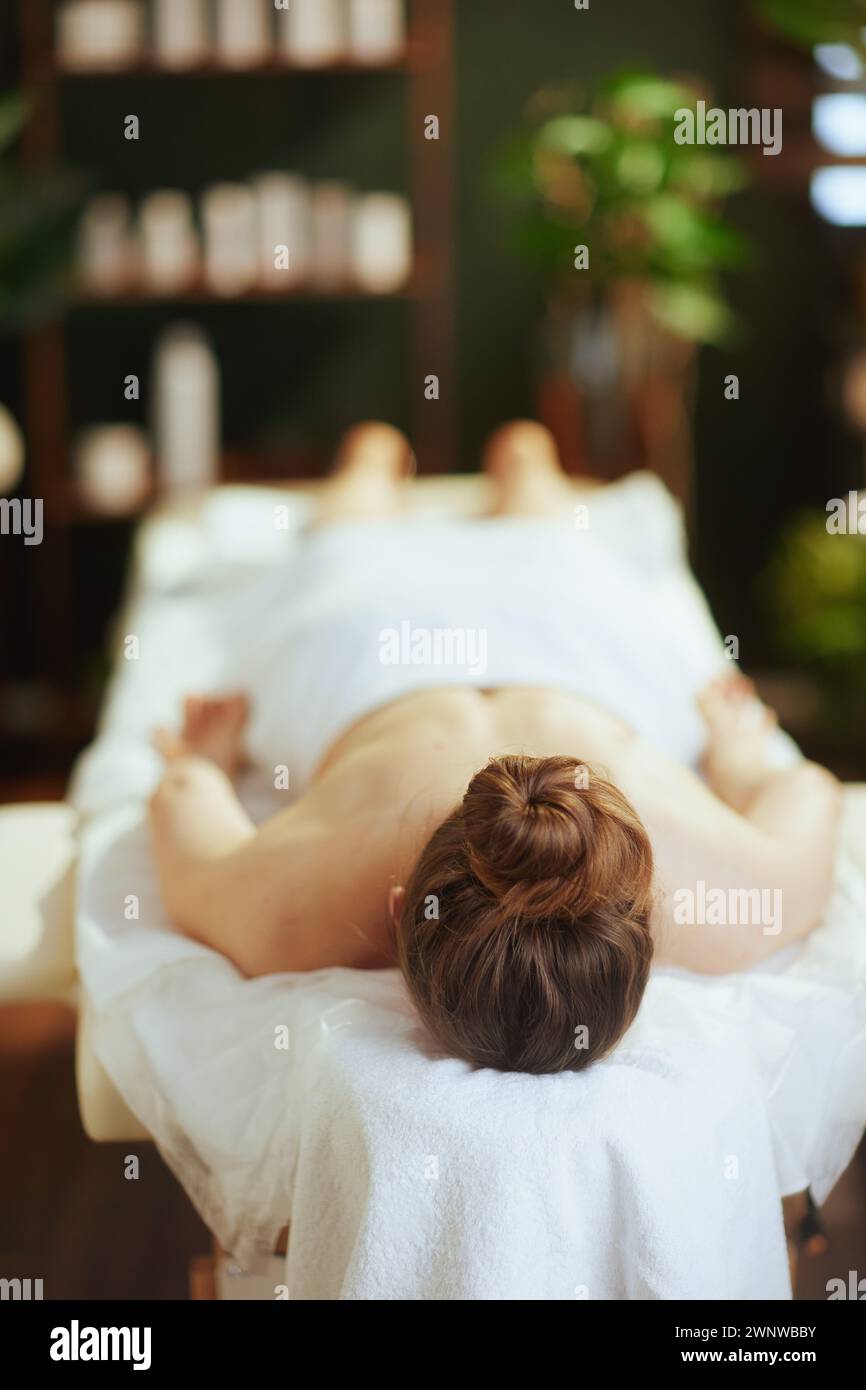 Gesundheitszeit. Entspannte, moderne Frau in Massageschrank, die auf einem Massagetisch liegt. Stockfoto