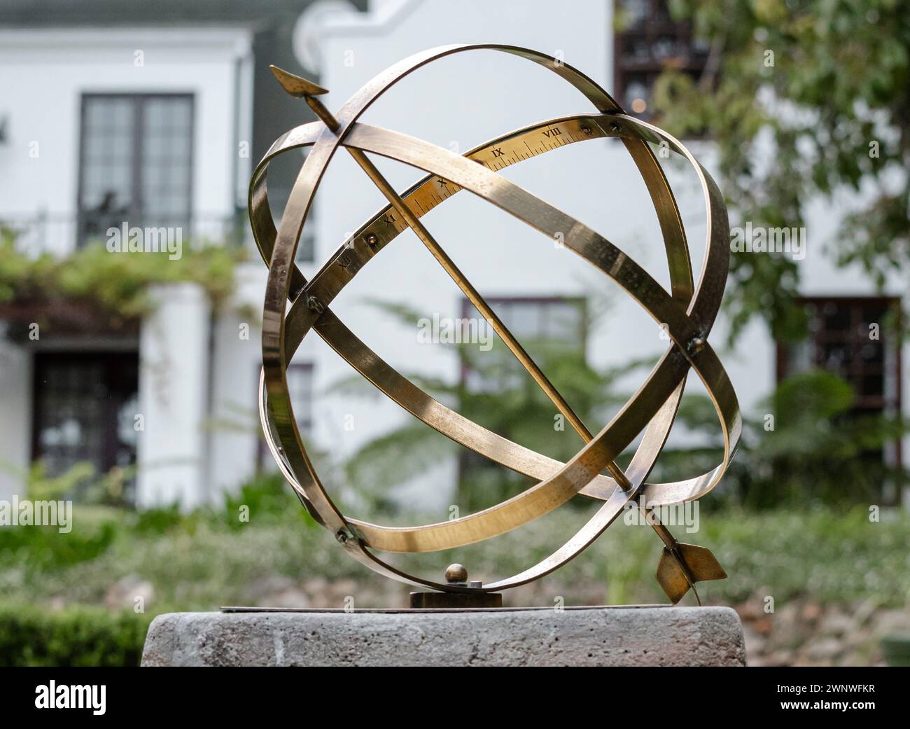 Große Gartenarmillariskugel mit Pfeil und römischen Ziffern. Hotelhinterhof Stockfoto