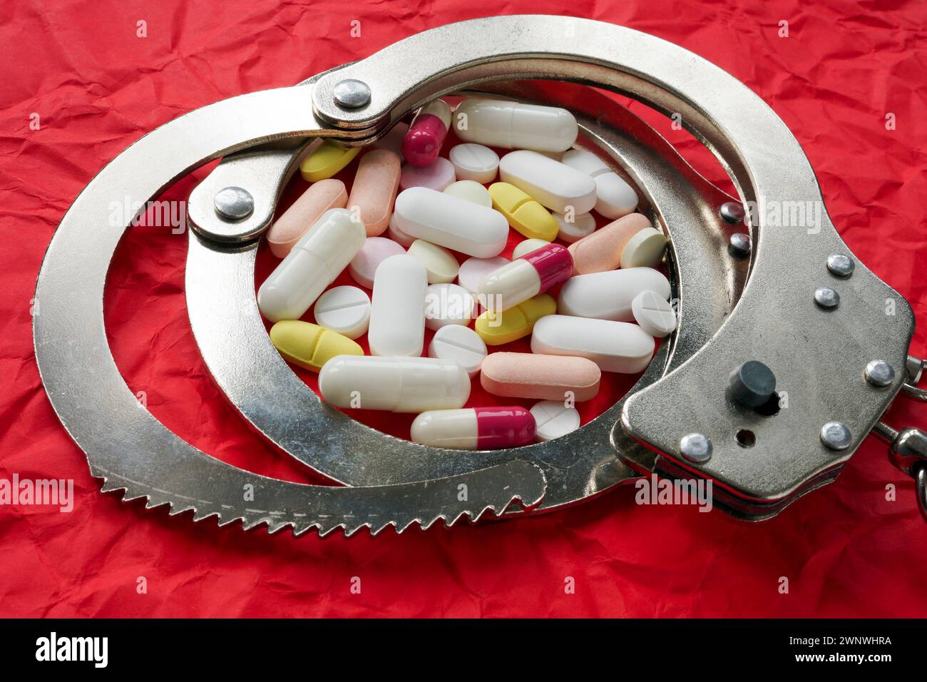 Handschellen und Pillen. Drogen und illegale Arzneimittel-Konzept. Stockfoto