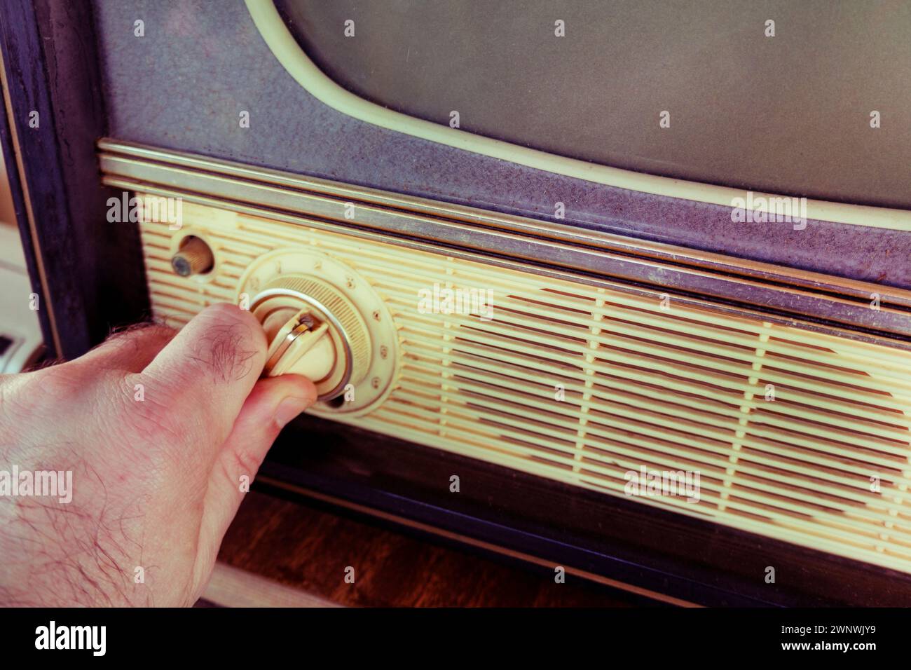 Die Hand wechselt die Sender auf dem alten Fernseher. Einschalten des alten Fernsehmonitors. Konzept-Viewer, TV-Kanalauswahl Stockfoto