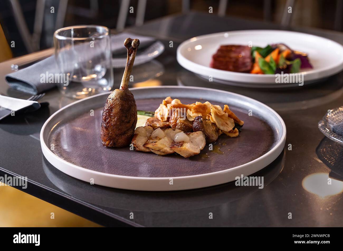 Elegantes Entenkonfit mit Verzierung auf einem stilvollen Teller - Gourmet-Dining-Erlebnis. Stockfoto