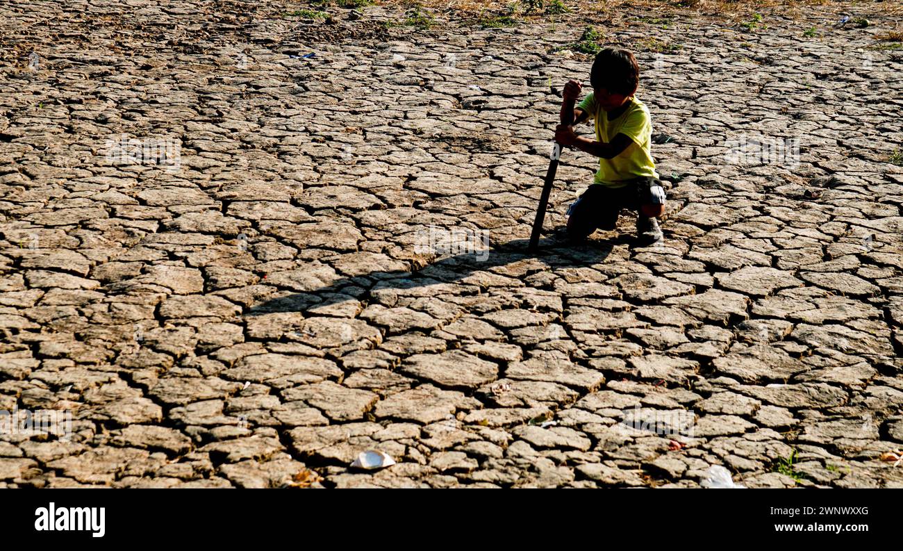Quezon City, Metro Manila, Philippinen. März 2024. Der Junge gräbt im TrockenReisfeld in Sitio Bakal, Brgy. Bagong Silangan und Chancen, Wasser in der aktuellen Dürre zu finden, inmitten des El NiÃ±o Phänomens. (Kreditbild: © EDD Castro/Pacific Press via ZUMA Press Wire) NUR REDAKTIONELLE VERWENDUNG! Nicht für kommerzielle ZWECKE! Stockfoto