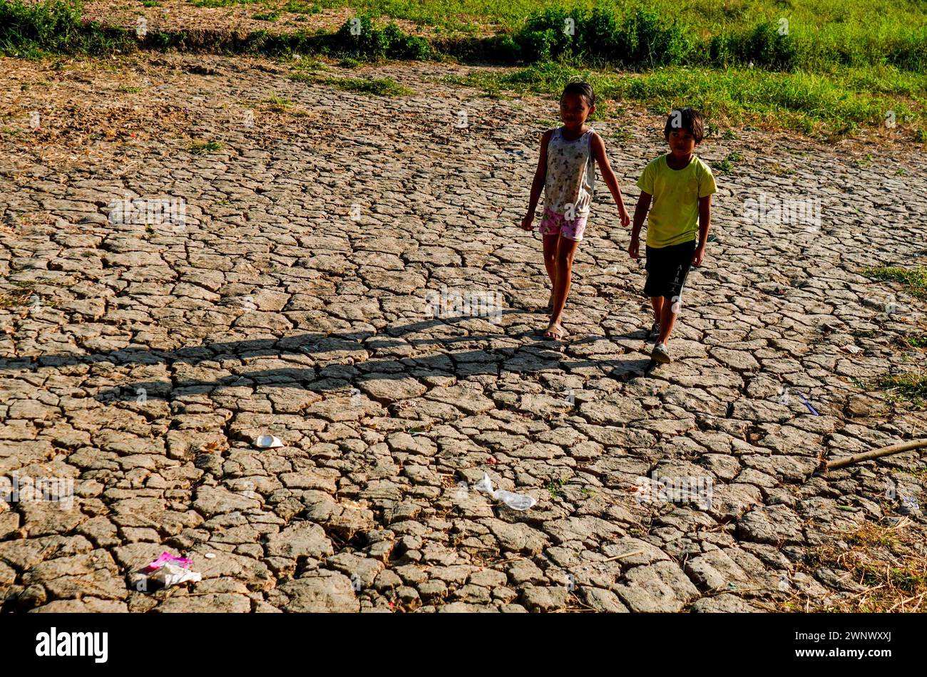 Quezon City, Metro Manila, Philippinen. März 2024. Kinderspaziergänge auf einem ausgetrockneten Reisfeld in Brgy. Bagong Silangan erlebt derzeit eine Dürre inmitten des El NiÃ±o Phänomens. (Kreditbild: © EDD Castro/Pacific Press via ZUMA Press Wire) NUR REDAKTIONELLE VERWENDUNG! Nicht für kommerzielle ZWECKE! Stockfoto