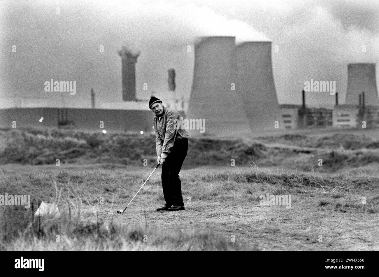 Kernkraftwerk Großbritannien. Windscale und Calder Nuclear Processing Plant. British Nuclear Fuels. Die Windscale Pfähle (einer auf diesem Foto) waren zwei luftgekühlte Graphitreaktoren auf dem Windscale-Kernkraftwerk in Cumberland (heute bekannt als Sellafield-Standort, Cumbria), Ein einheimischer Mann, der auf dem sogenannten toxischen Golfplatz spielte. Windscale, Cumbria, England 1983. HOMER SYKES AUS DEN 1980ER JAHREN Stockfoto