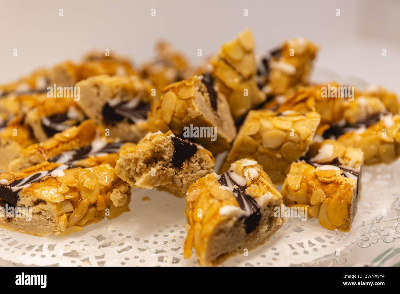 Horizontales Foto eine verführerische Auswahl an arabischem Gebäck, gekrönt mit Mandelsplittern und einem Schokoladengriß, präsentiert auf einem zarten Spitzenpapier. Essen und Stockfoto