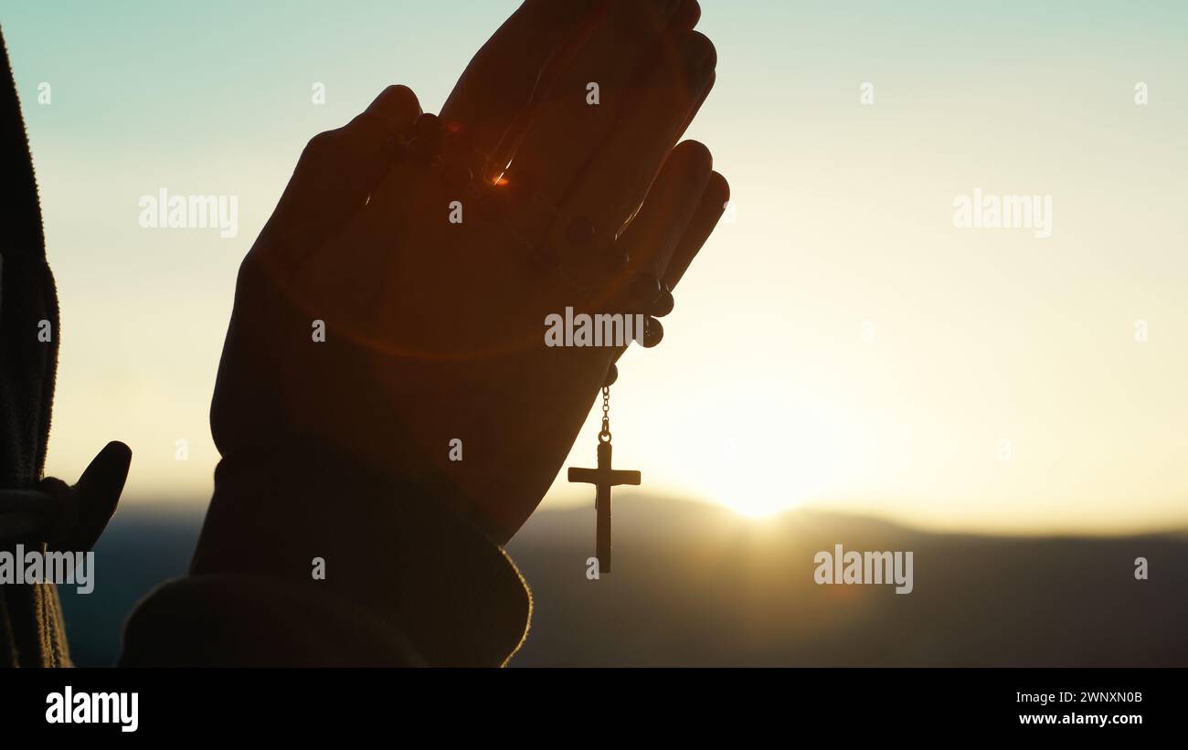 Der Mann betet bei Sonnenuntergang mit Rosenkranz Stockfoto