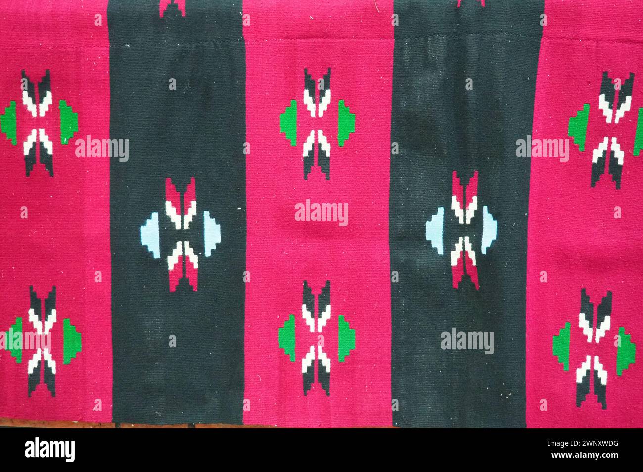 Handgewebtes Kelims-Muster. Traditionelle serbische Volksmuster auf dem Teppich. Rote, rosa und schwarze vertikale Streifen. Rhombisch dekorativ Stockfoto