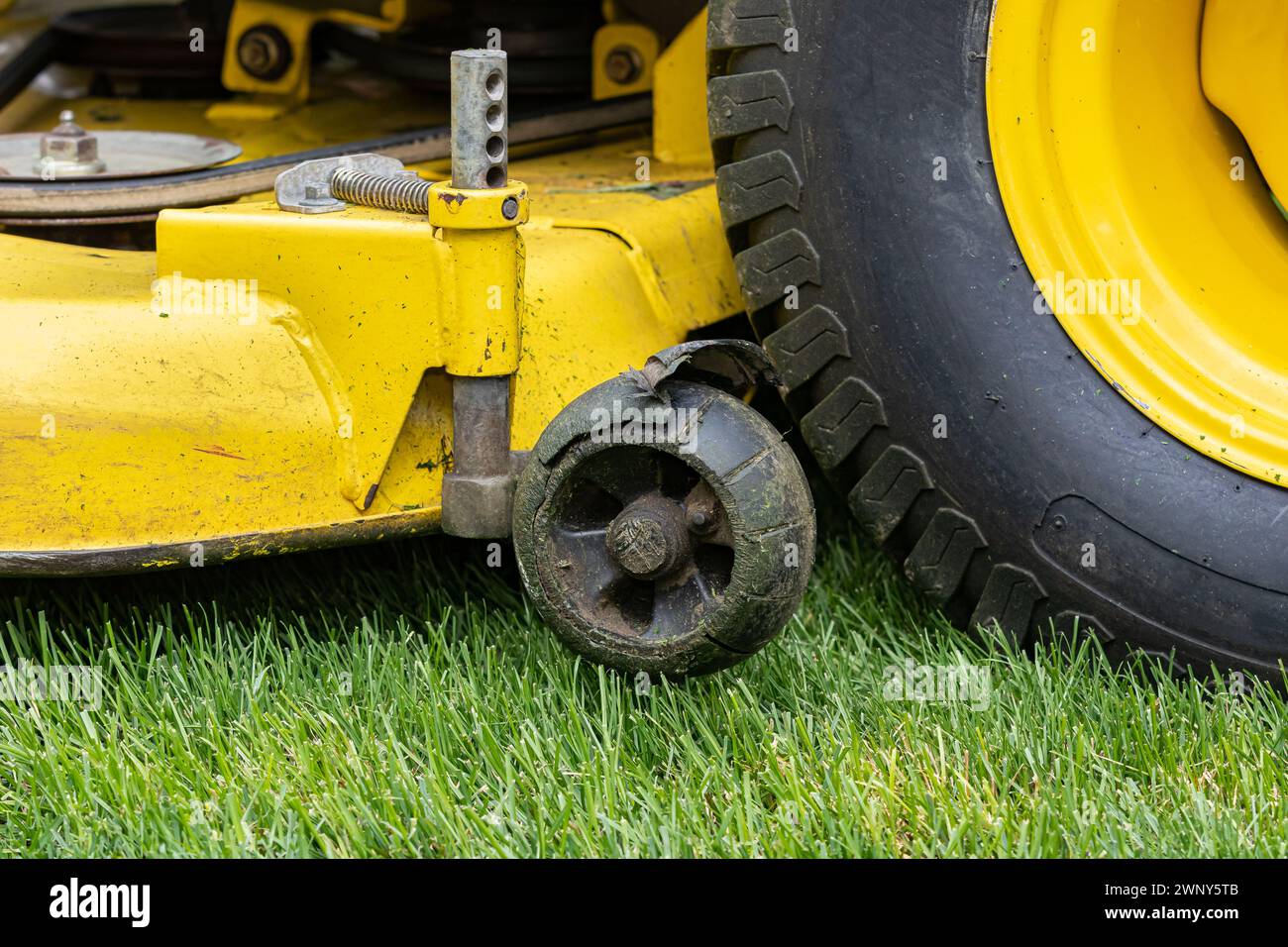 Stützrad des Rasenmähers gebrochen und beschädigt. Wartungs-, Reparatur- und Servicekonzept für Rasenanlagen. Stockfoto