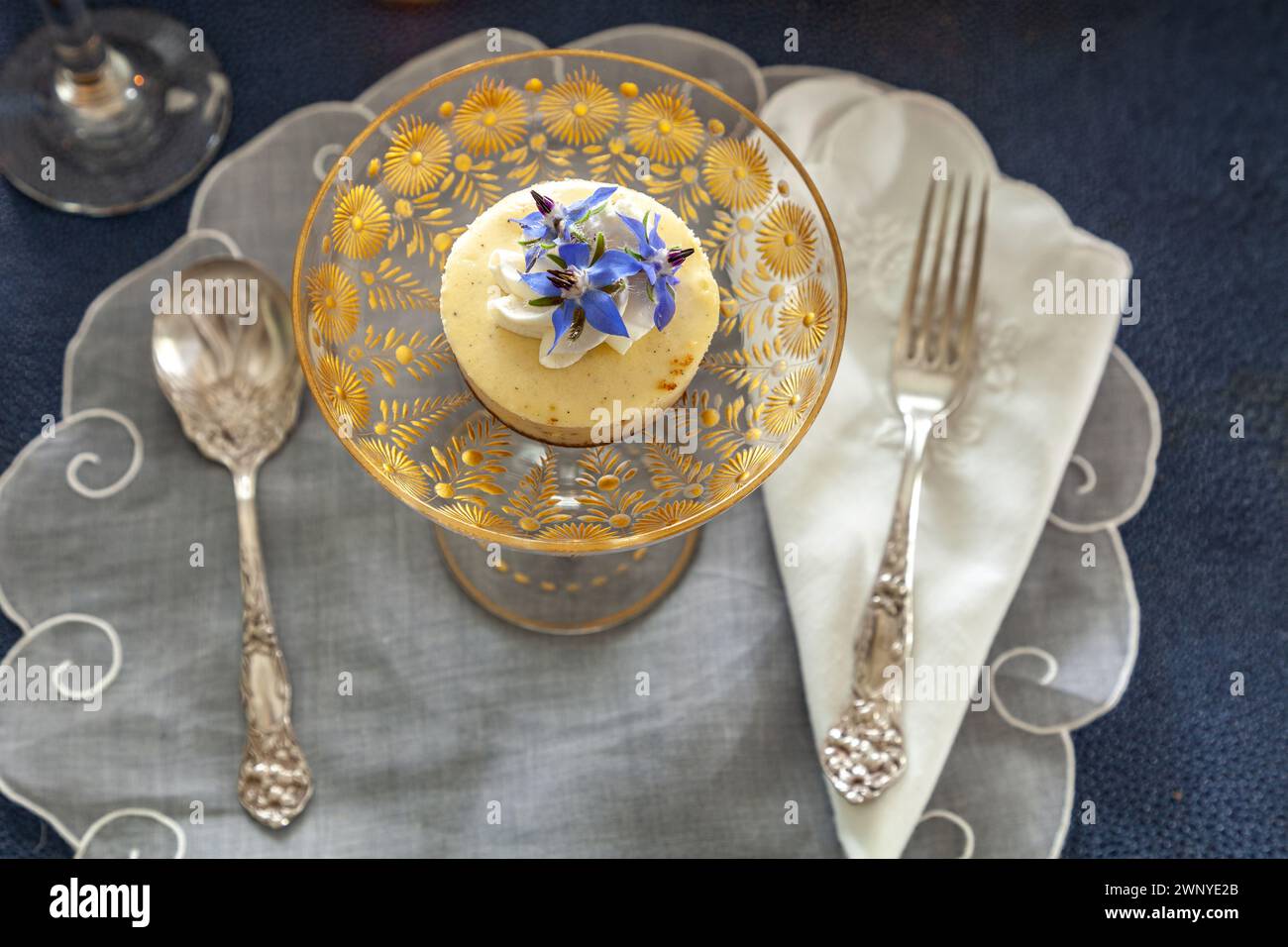 Käsekuchen-Dessert und Schlagsahne mit Goldstaub auf einer schicken Kristallglasschale mit Goldätzung. Stockfoto