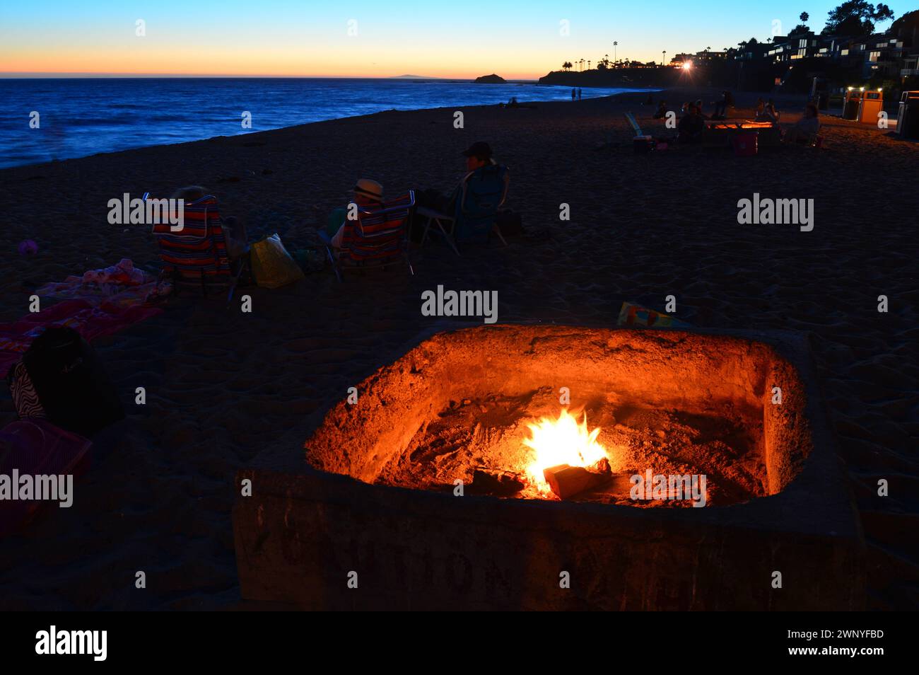 Eine Feuerstelle leuchtet bei Sonnenuntergang entlang der Küste in Laguna Beach, Kalifornien. Stockfoto