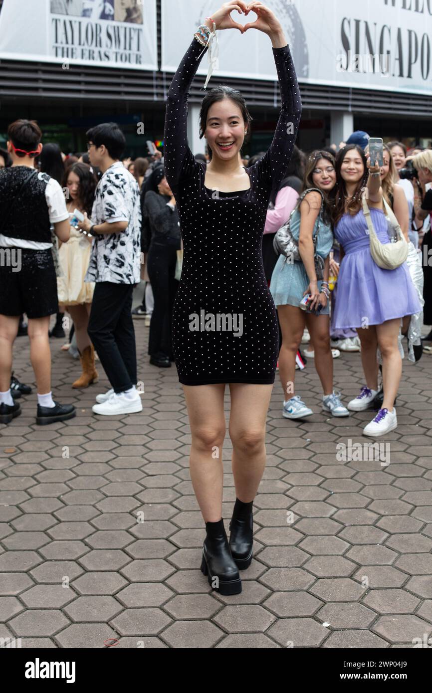 März 2024. Eine hübsche Frau verkleidet sich in einem einteiligen Polka-Kleid. Hände hoch, Finger in Herzform. Taylor Swift The Eras Tour, Singapur. Stockfoto