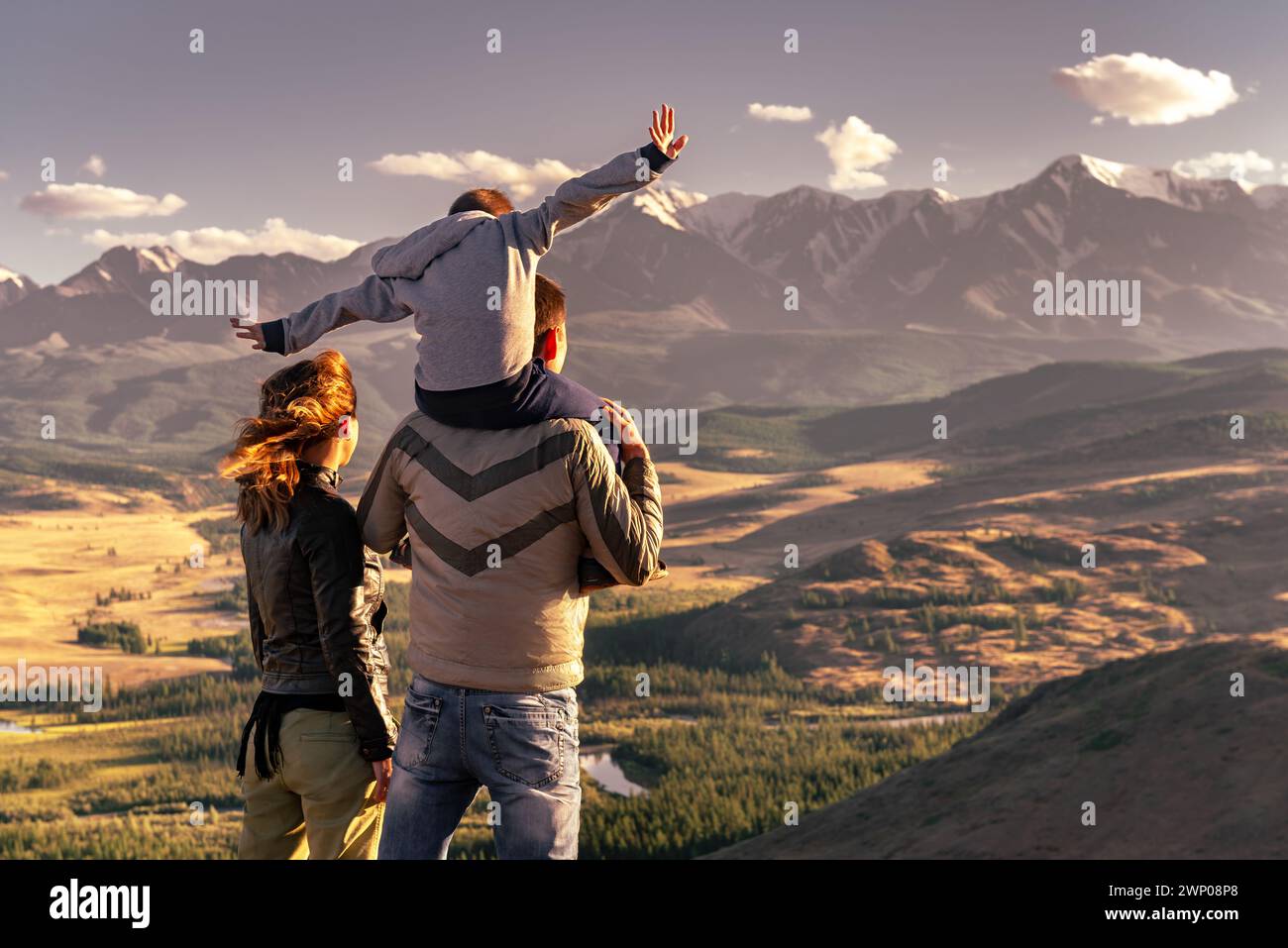 Glückliche Familie mit Mutter, Vater und Sohn blicken auf die Berge und genießen den Sonnenuntergang Stockfoto