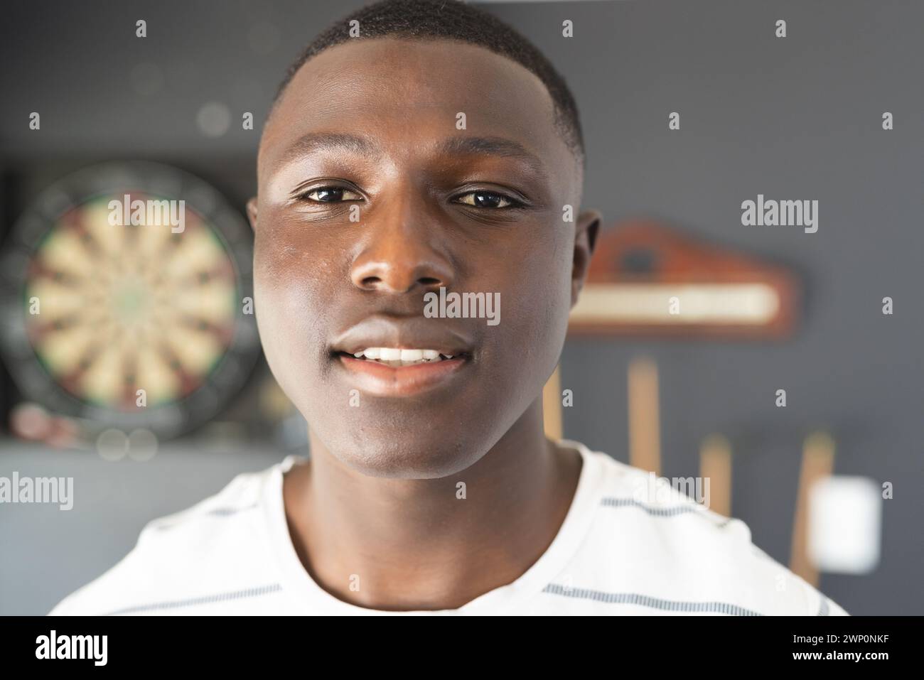Ein junger Afroamerikaner mit einem angenehmen Ausdruck steht drinnen Stockfoto