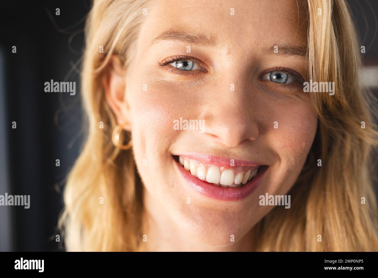 Die junge kaukasische Frau mit blonden Haaren und blauen Augen lächelt in die Kamera Stockfoto