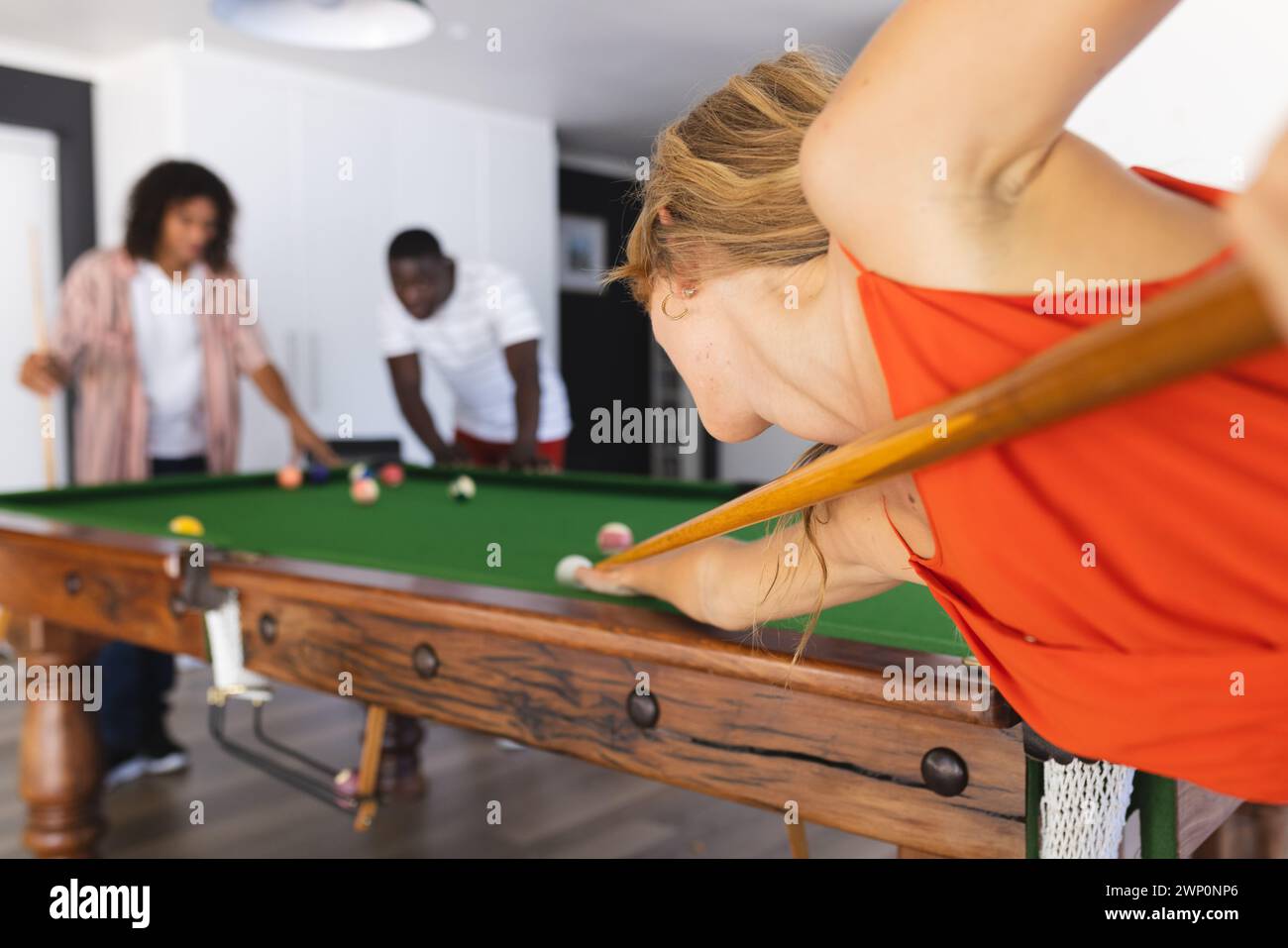 Junge kaukasische Frau spielt Billard und konzentriert sich auf ihren Schuss Stockfoto
