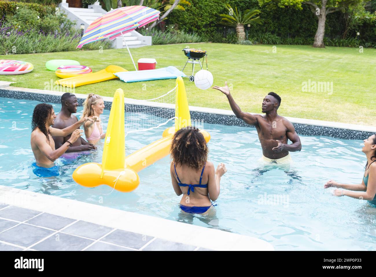Verschiedene Freunde genießen eine Poolparty mit einem jungen afroamerikanischen Mann, der anregend Gesten gibt Stockfoto