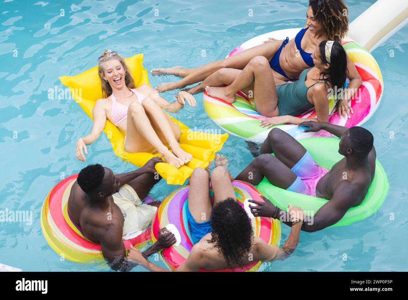 Verschiedene Gruppen von Freunden genießen eine Poolparty auf farbenfrohen Floaties Stockfoto