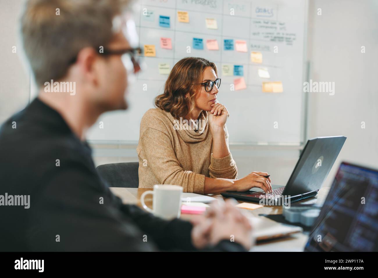 Fachleute in einem vielfältigen Technologieunternehmen nehmen an gemeinsamen Diskussionen Teil und arbeiten in einem Vorstandssitz zusammen. Sie konzentrieren sich auf Softwareprojekte, sie utili Stockfoto