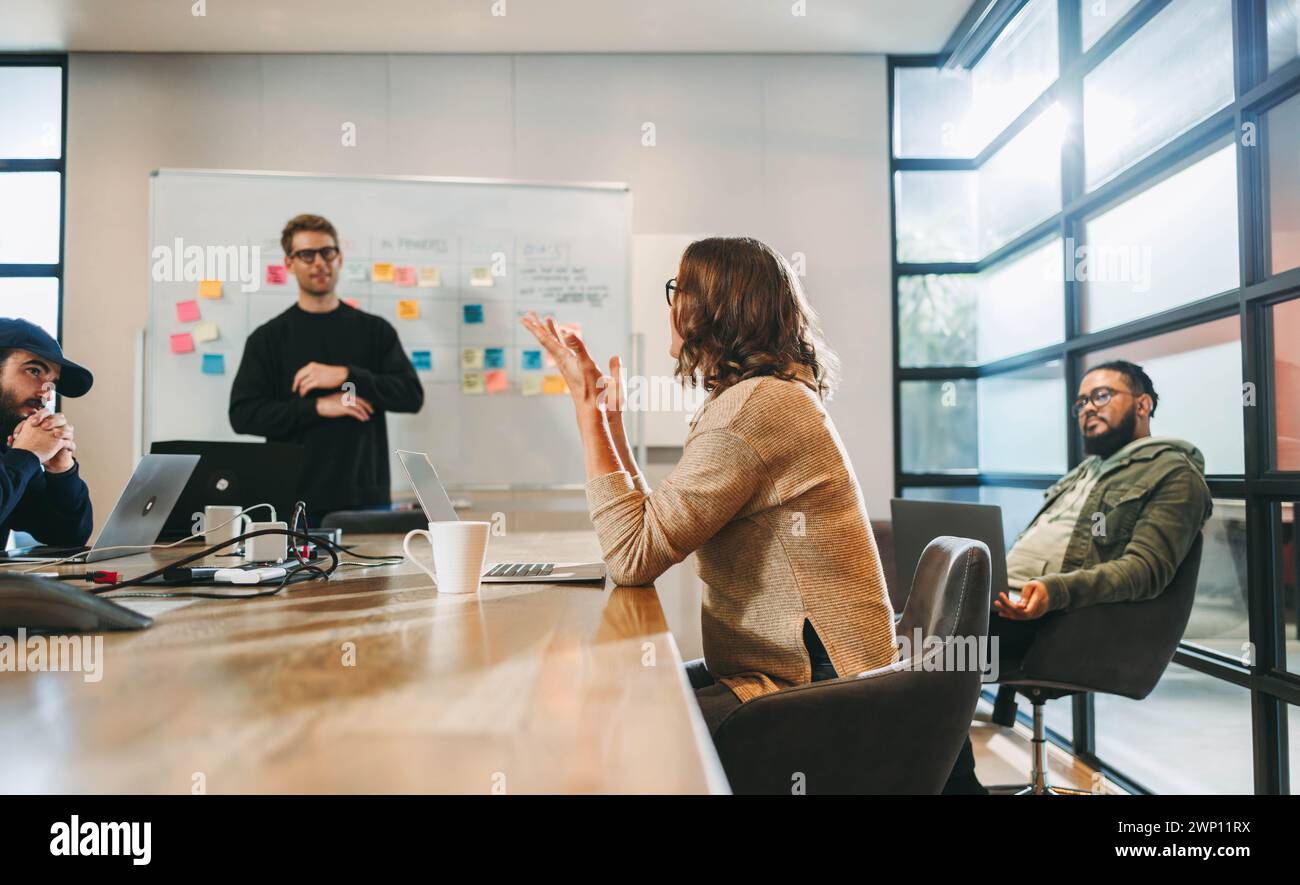 Verschiedene Fachleute führen eine gemeinsame Diskussion. Sie sitzen in einem gut beleuchteten Sitzungssaal und sammeln ein Brainstorming für Projektmanagement und Softwareentwickler Stockfoto