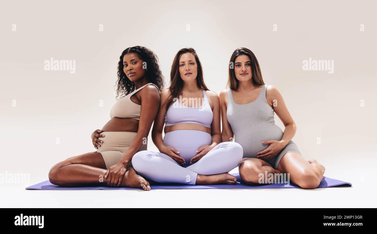 Werdende Mütter nehmen an Yoga Teil und pflegen ihr Baby in einem vielseitigen Fitnesskurs. Werdende Mütter priorisieren die Schwangerschaftsvorsorge im dritten Trimenon Stockfoto