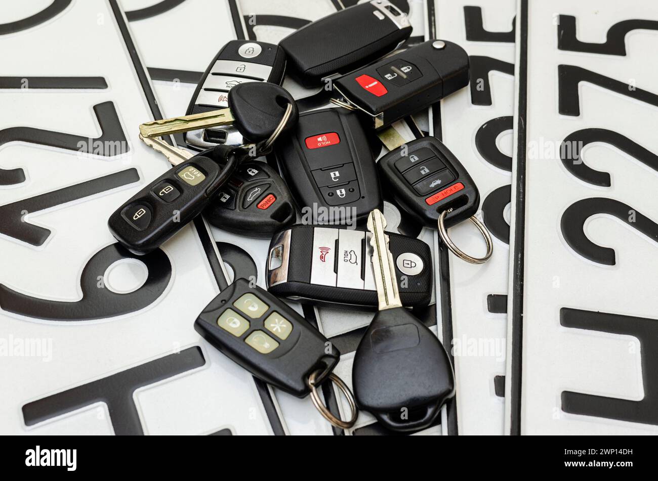 Nahaufnahme von Autoschlüsseln und Alarmanhängern auf dem Hintergrund von Autokennzeichen Stockfoto