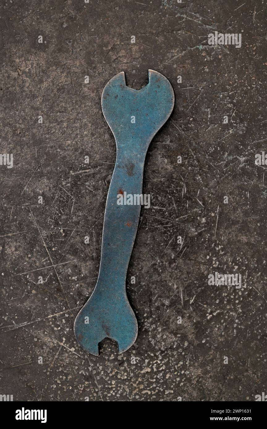 Kleines doppelseitiges blaues graues Metall, das auf angetriebenem schwarzem Metall liegt Stockfoto