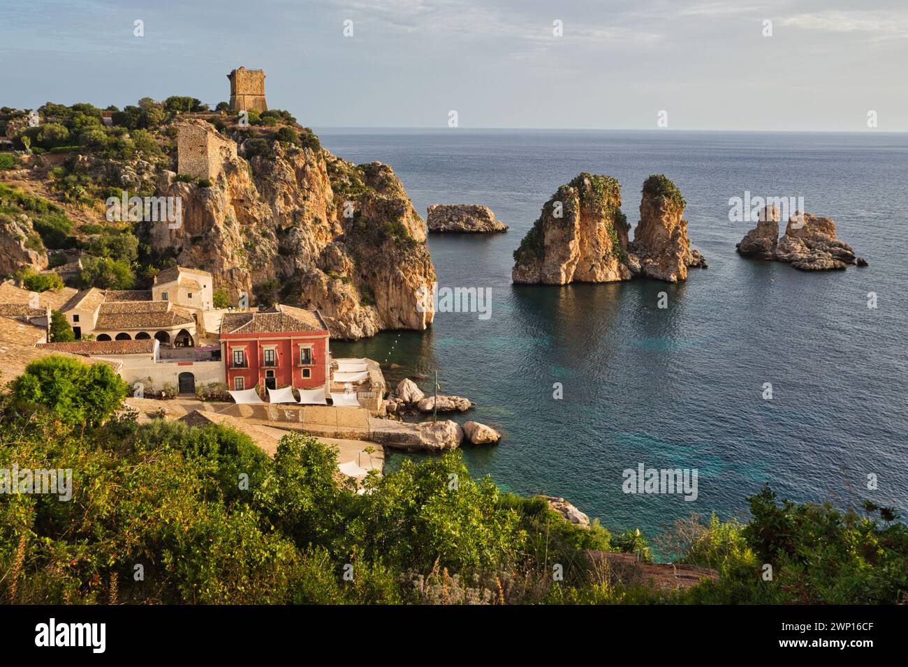 Tonnara di Scopello, Sizilien, früh am Morgen mit den faraglioni, Felsentürmen, im Meer und Verteidigungsturm auf dem Hügel Stockfoto