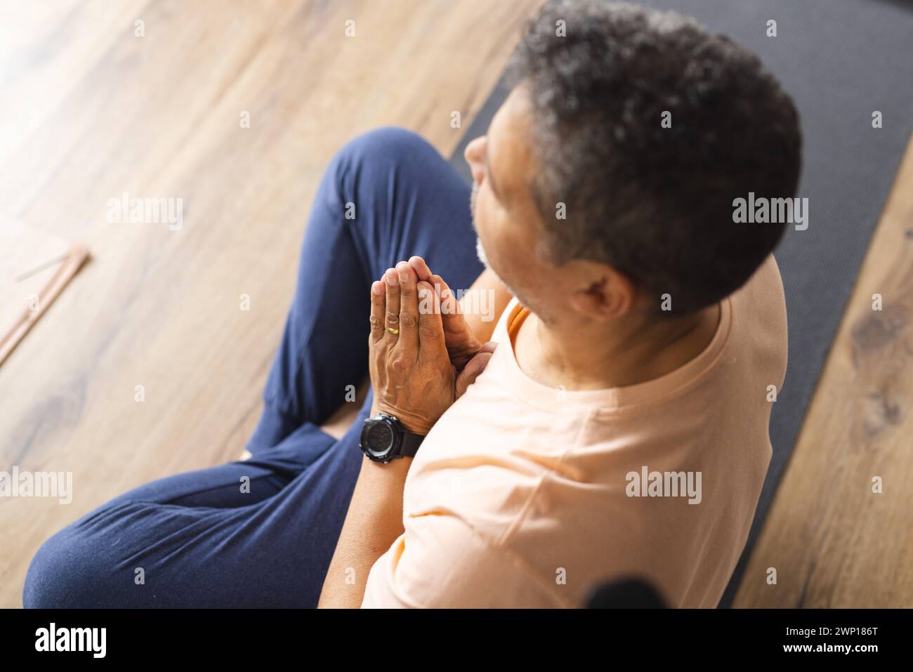 Birassischer Seniorenmann mit grauen Haaren übt Yoga in einer ruhigen Innenumgebung Stockfoto