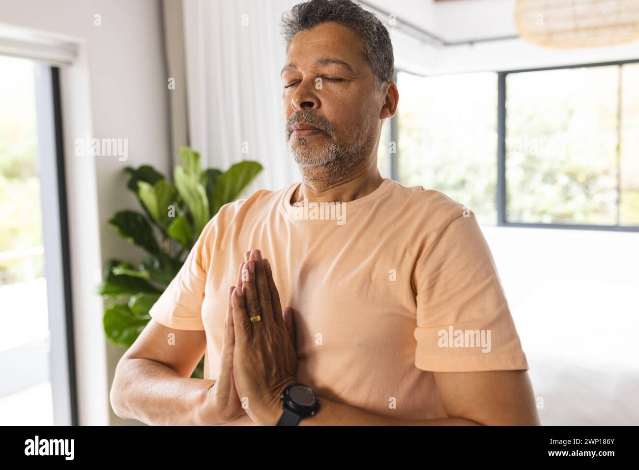 Biracial Senior man übt Meditation mit Händen in Gebetsposition, Augen geschlossen Stockfoto
