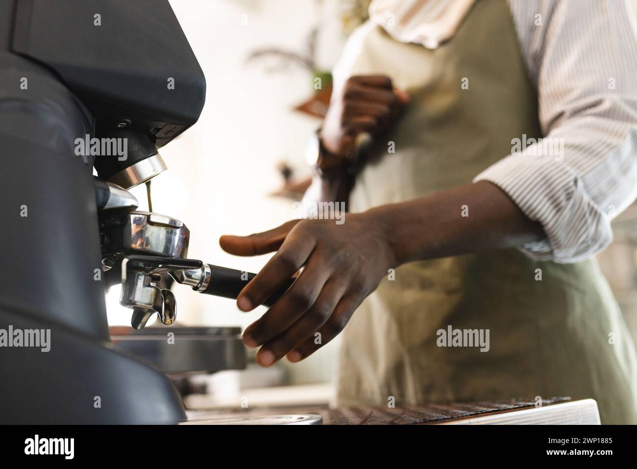 Der afroamerikanische Barista bedient in einem Café eine Espressomaschine Stockfoto