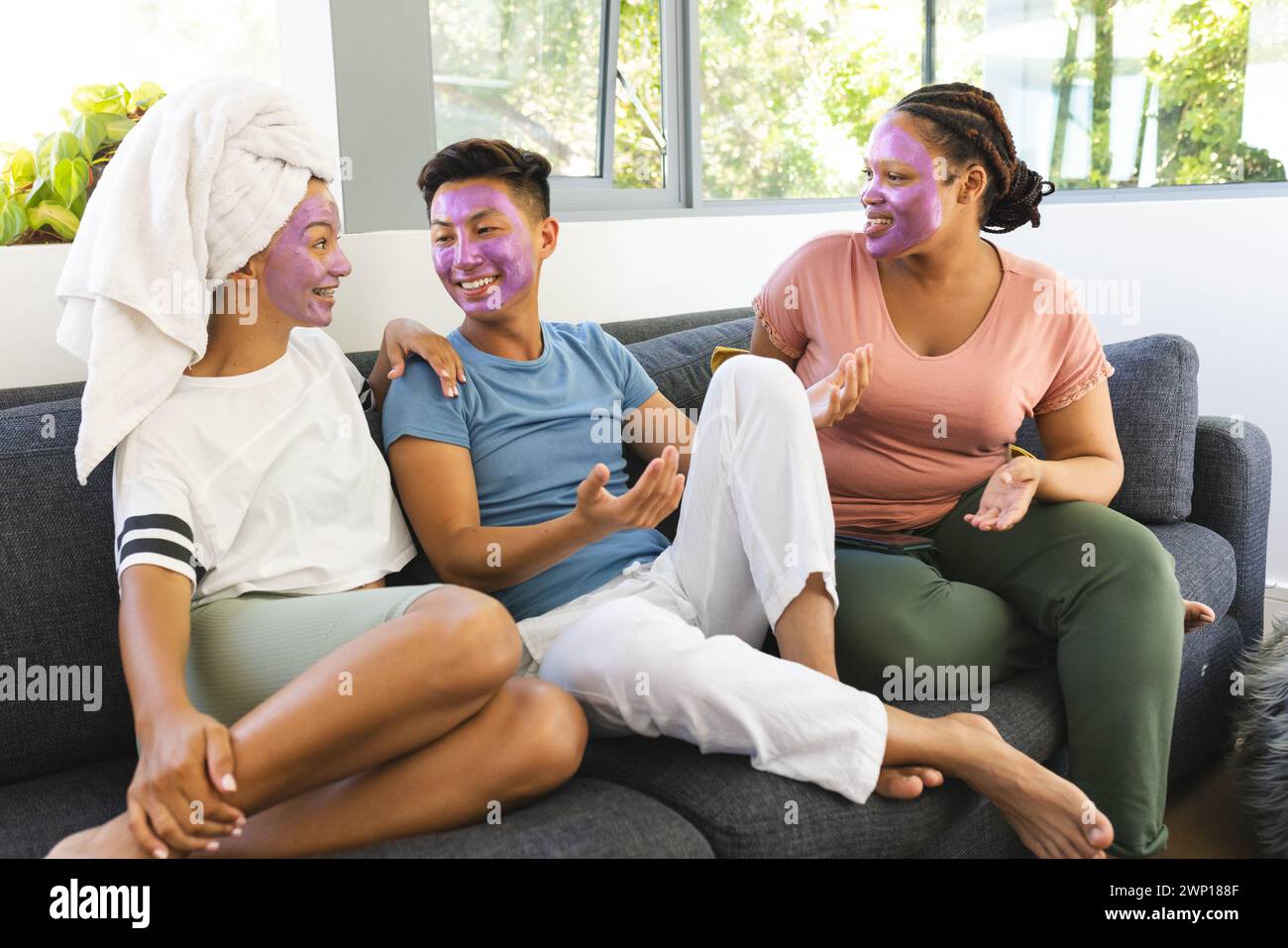 Drei Freunde genießen einen Spa-Tag zu Hause und lachen zusammen auf einer Couch Stockfoto