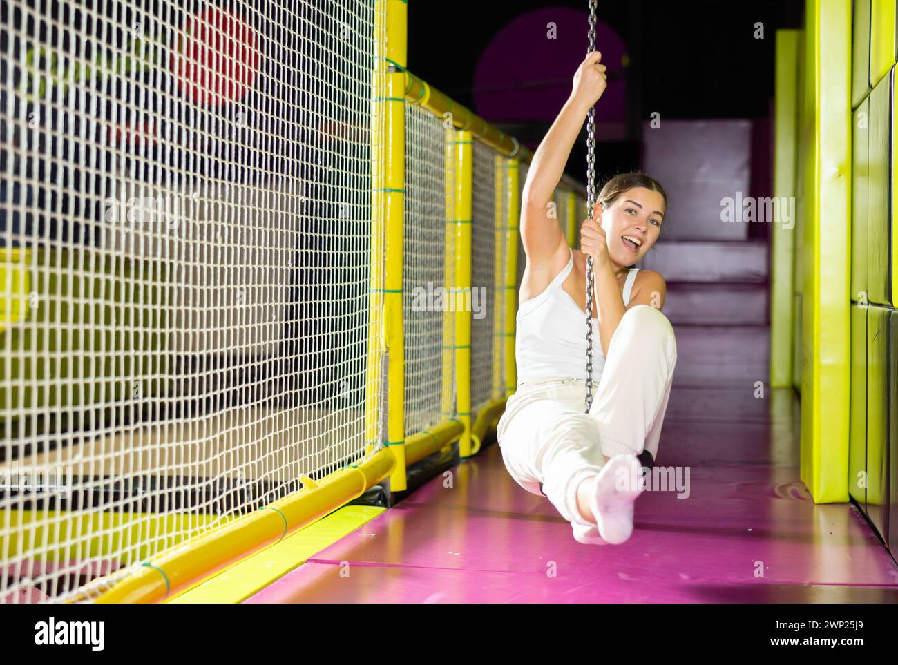 Fröhliches junges Mädchen reitet Seilrutsche im Indoor-Vergnügungszentrum Stockfoto