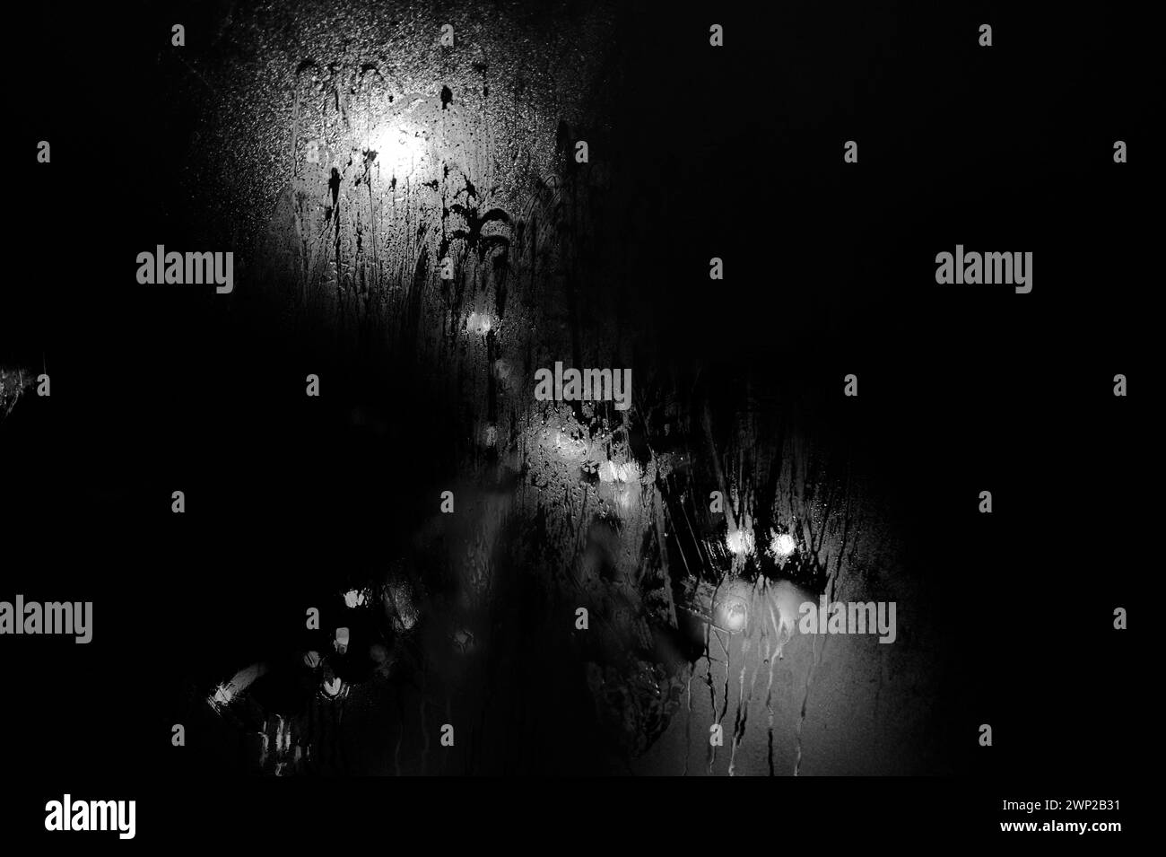 Schwarz-weiß, winterlich regnerische Nacht Blick durch Busfenster, Straßenlaternen, Autoscheinwerfer, Straßenlaternen, Ampeln, nebliges Fenster und Regentropfen Stockfoto